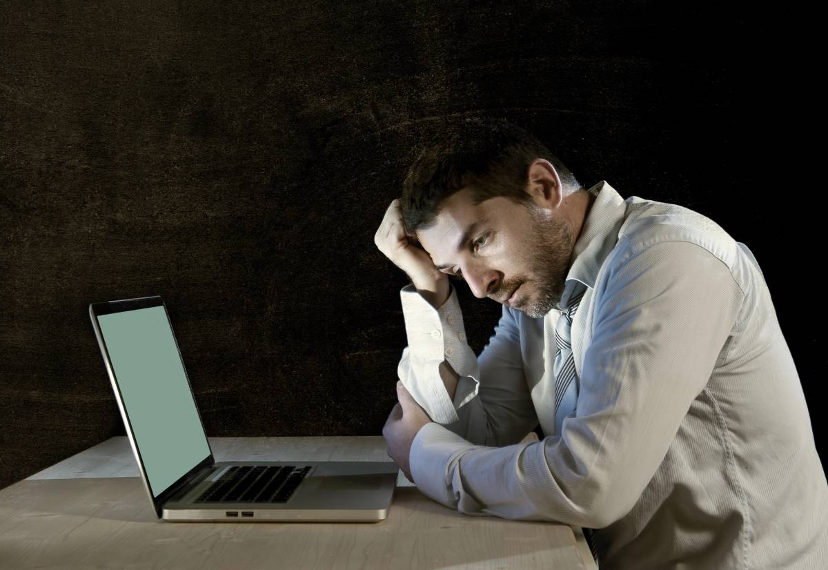 A stressed man at desk with laptop, needing Kyle IT solutions.