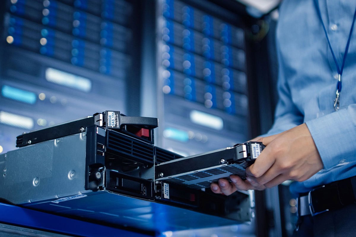 An IT technician is installing a drive in a server in a data center.