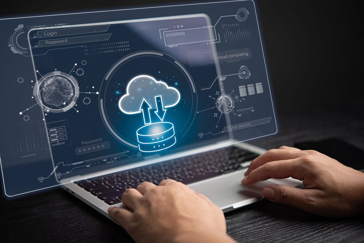 A person is using a laptop showing a server transferring data to a cloud.